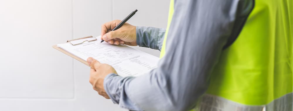man in blue button up writting on clip board.